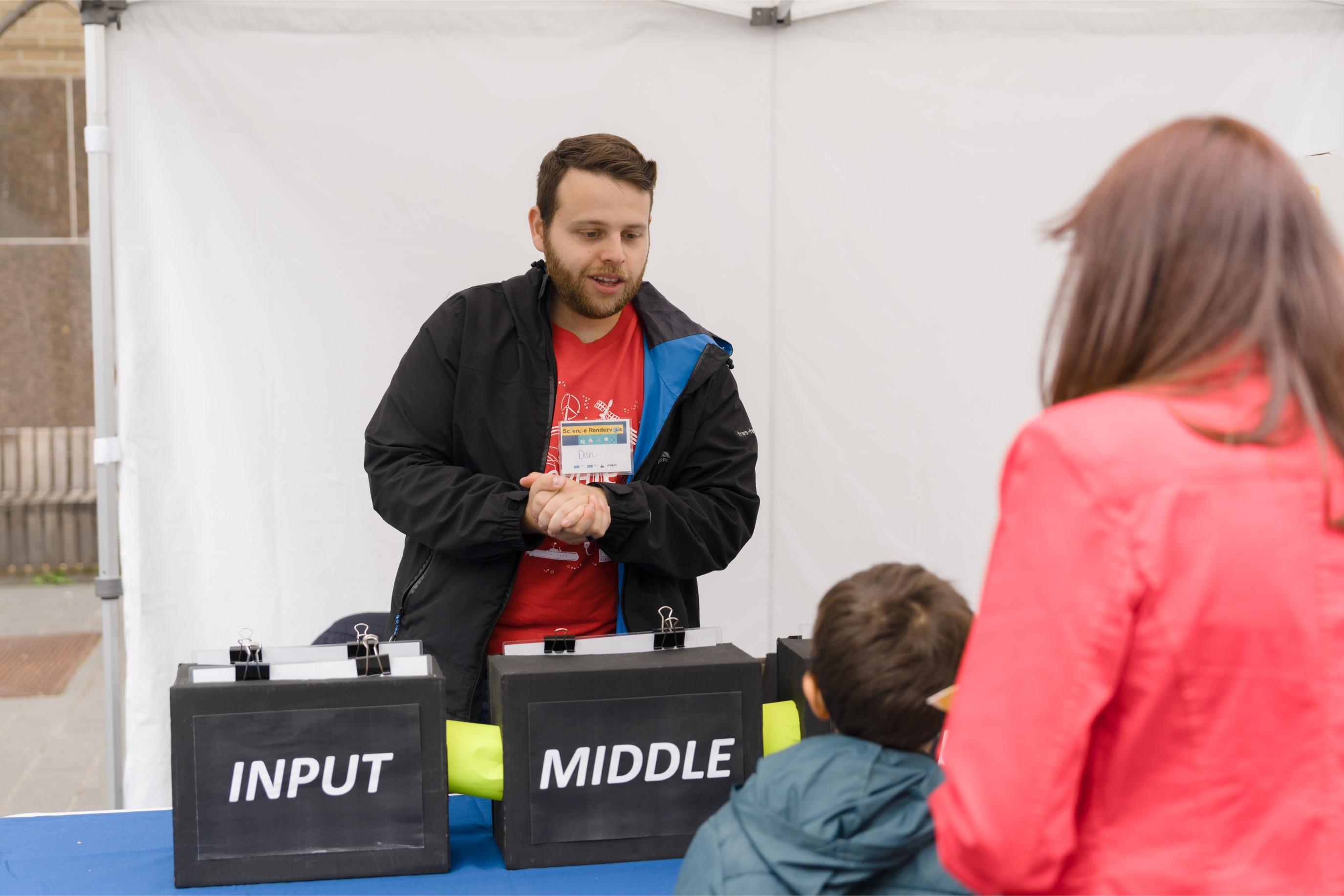 A volunteer talking to the participants at the Deep Learning Booth.